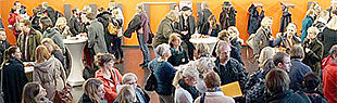 Das Foto zeigt viele Menschen im Foyer des Audimax verteilt an einigen Stehtischen.