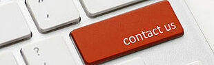 Das Bild zeigt einen Ausschnitt einer Tastatur, bei dem eine Taste durch eine rote Taste mit der Aufschrift contact us ersetzt ist. 