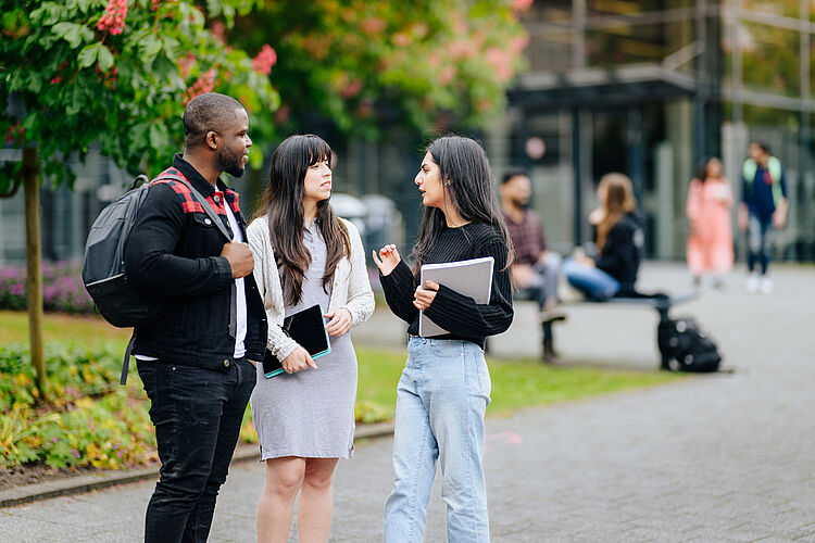 Drei Personen im Gespräch draußen auf dem Campus der Universität Paderborn.